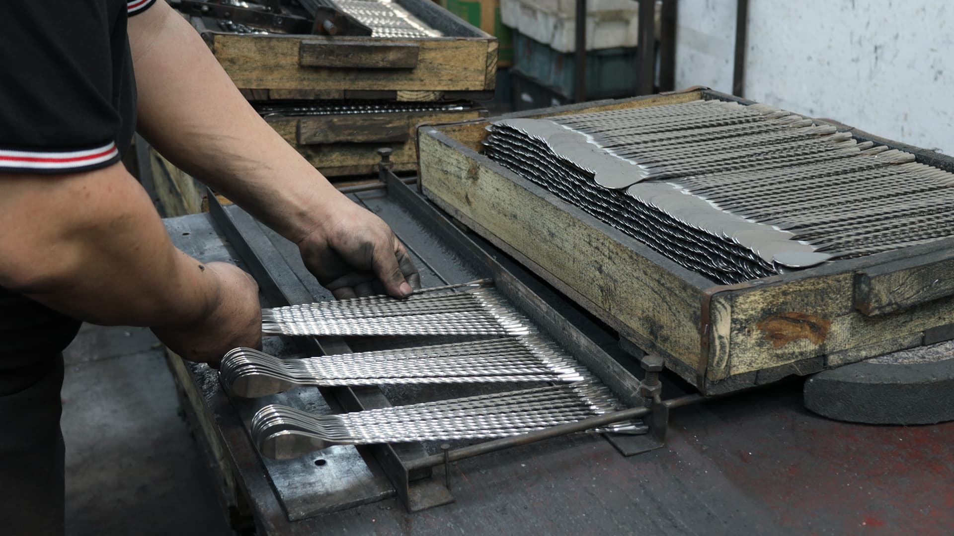 Skilled worker arranging stainless steel utensil handles in unitedpeople factory, demonstrating mass production capacity and strict quality control for international kitchenware orders.
